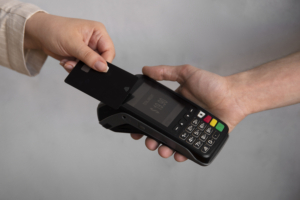 Someone holding a payment card to a PCI DSS compliant payment terminal.
